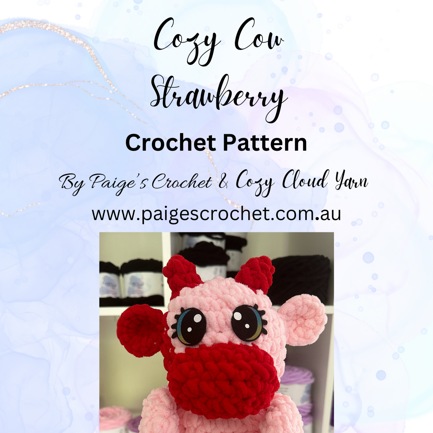 A crochet pattern for a strawberry-colored cow with a pink body and red accessories, named Cozy Cow- Strawberry. The image features the finished product, not the actual pattern.