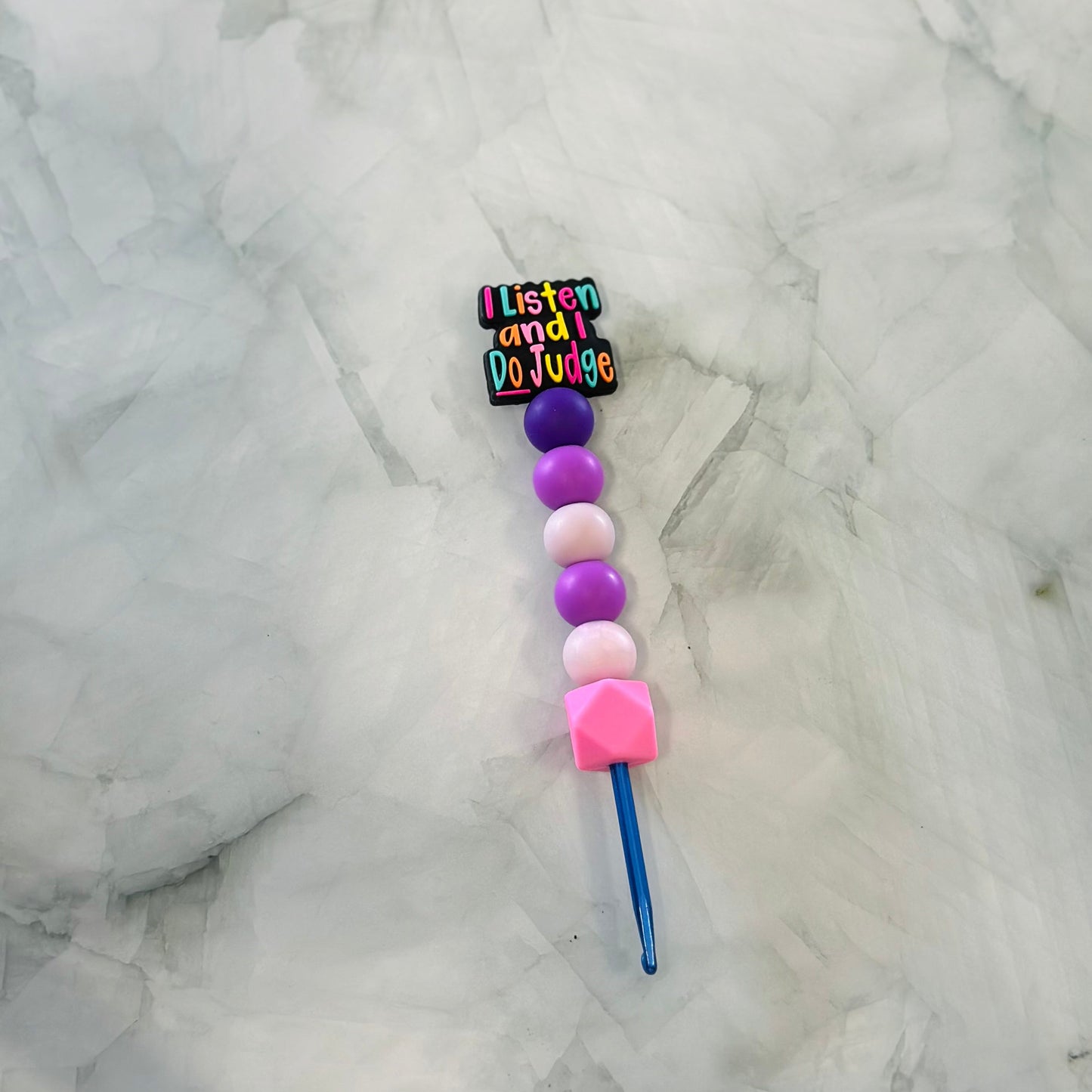 Colorful beaded crochet hook with a colorful phrase focal bead on a marble background. Chenille yarn/ Plush Yarn