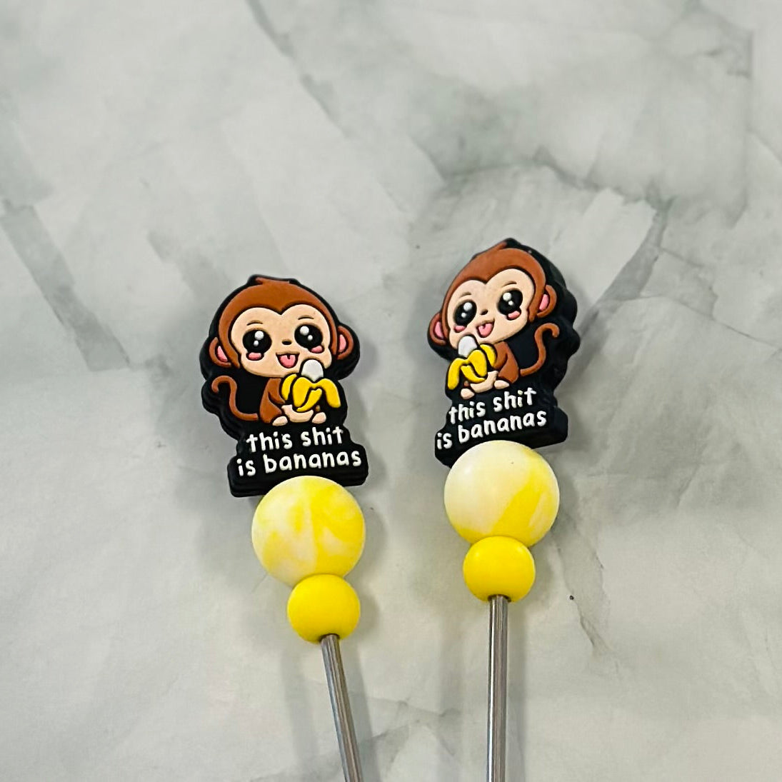 Two cartoon monkey-themed stitch sticks with yellow beads on a marble background.
amigurumi chenille, plush yarn