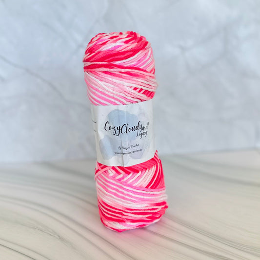 Ball of pink and white yarn with a label on a textured surface