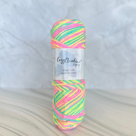 Multicolored skein of acrylic 10ply yarn with a label on a light background. Yellow pink green mix