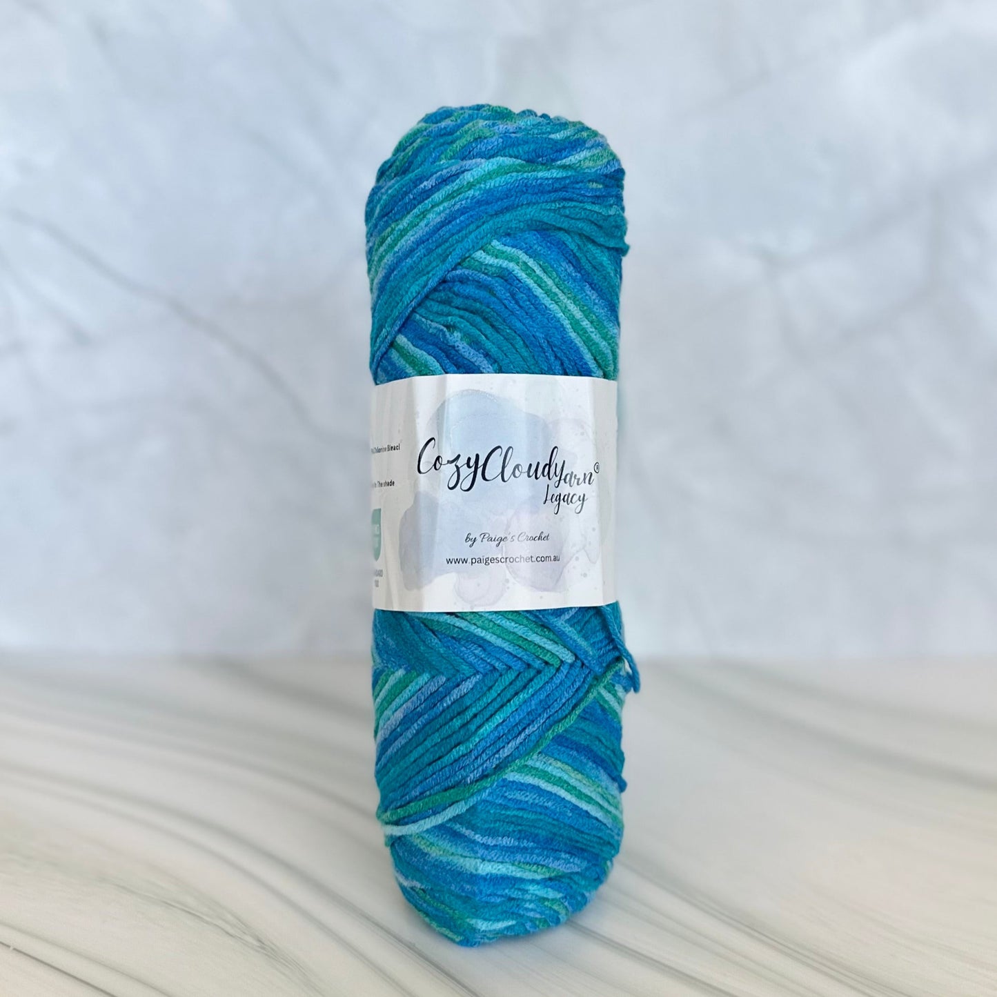 Blue and green skein of 10 ply acrylic yarn with a label on a white background