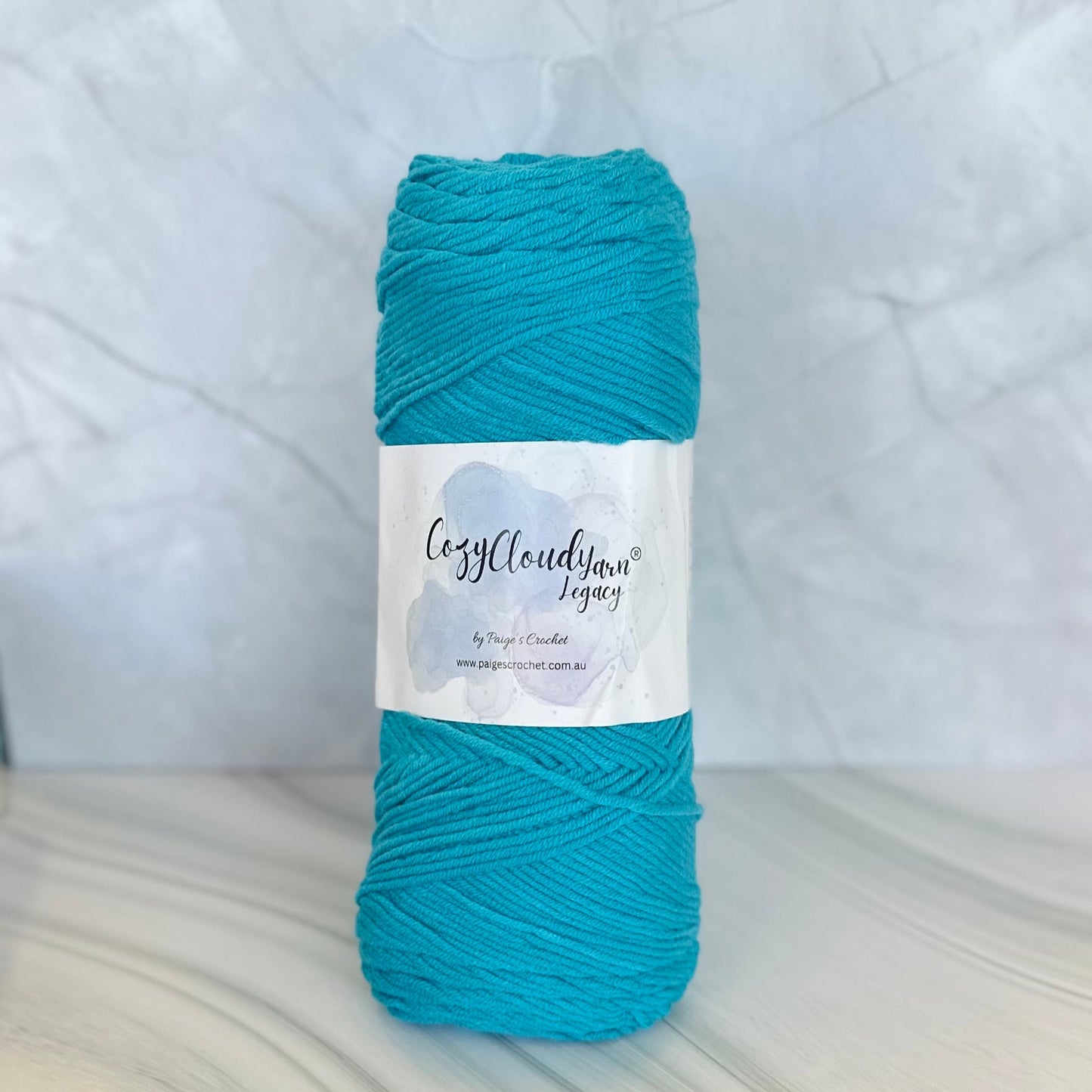 Turquoise skein of yarn with a label on a white background