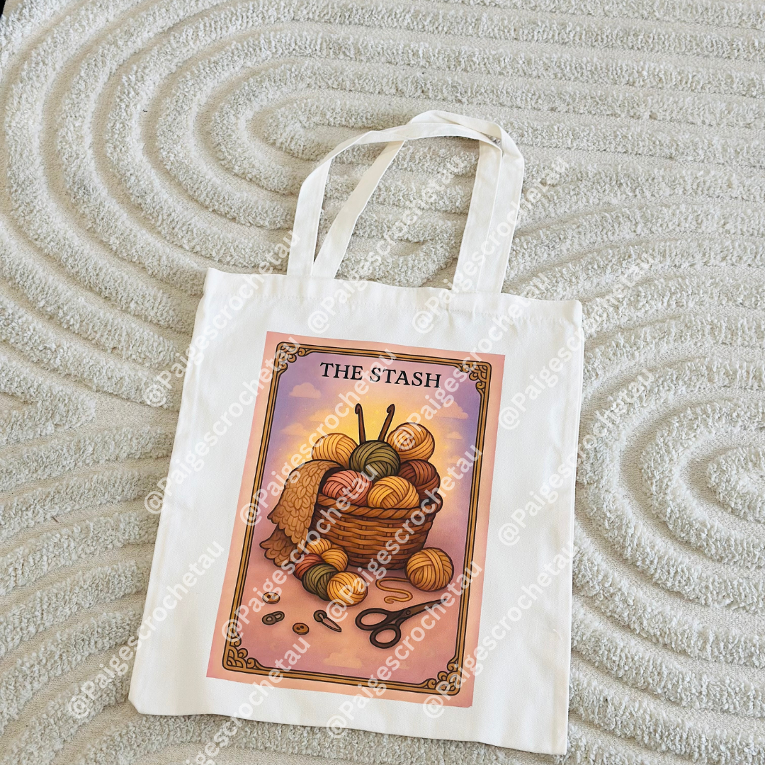A tarot-inspired Cozy tote bag with soft, calming yarn artwork in warm pastel tones, DTF printed on a durable tote for crochet and yarn lovers