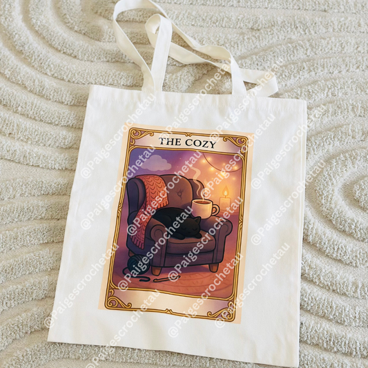 A tarot-inspired Cozy tote bag with soft, calming yarn artwork in warm pastel tones, DTF printed on a durable tote for crochet and yarn lovers
