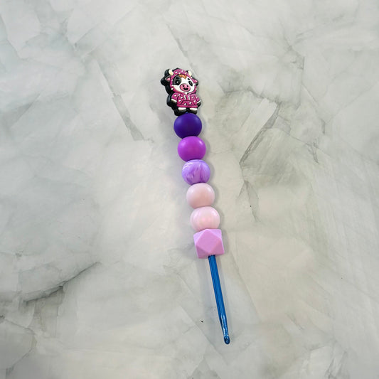 Decorative crochet hook with colorful beads on a marble surface