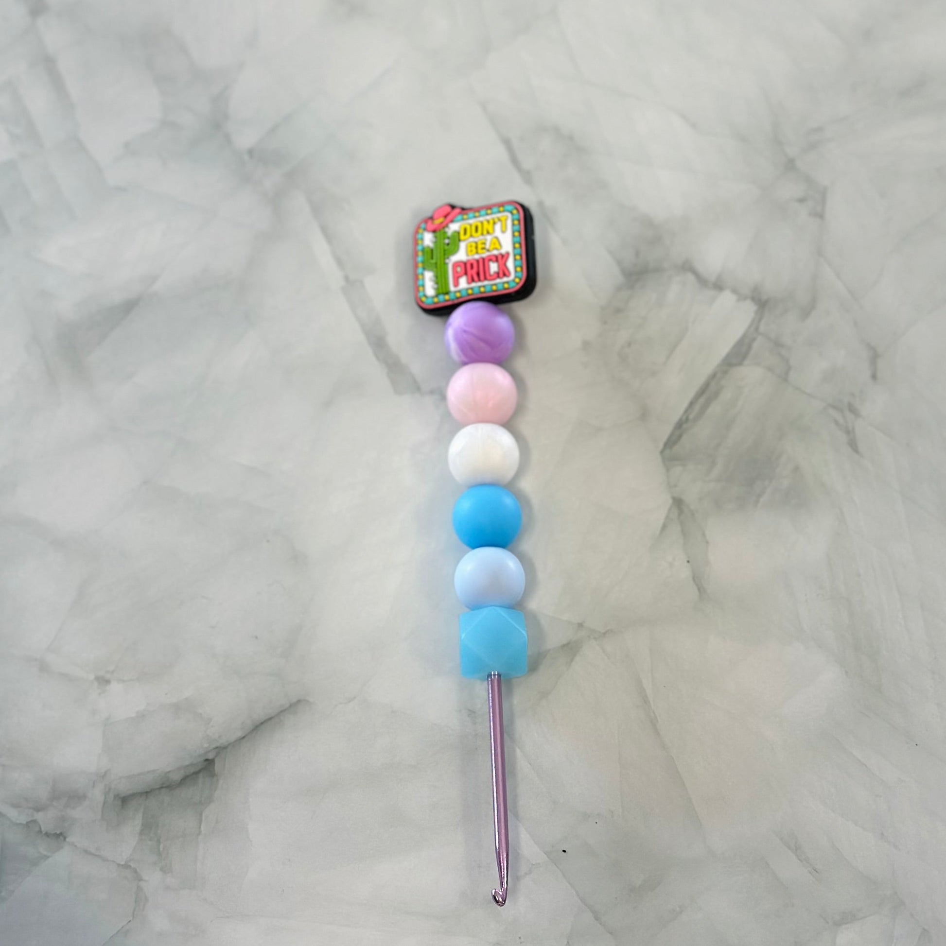 Crochet hook with colorful foam tips on a marble surface