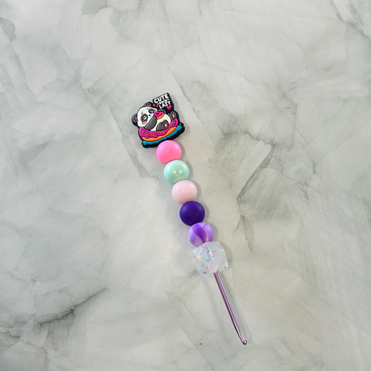 Decorative Crochet hooks with colorful beads and panda charm on a marble background plush yarn, chenille yarn 