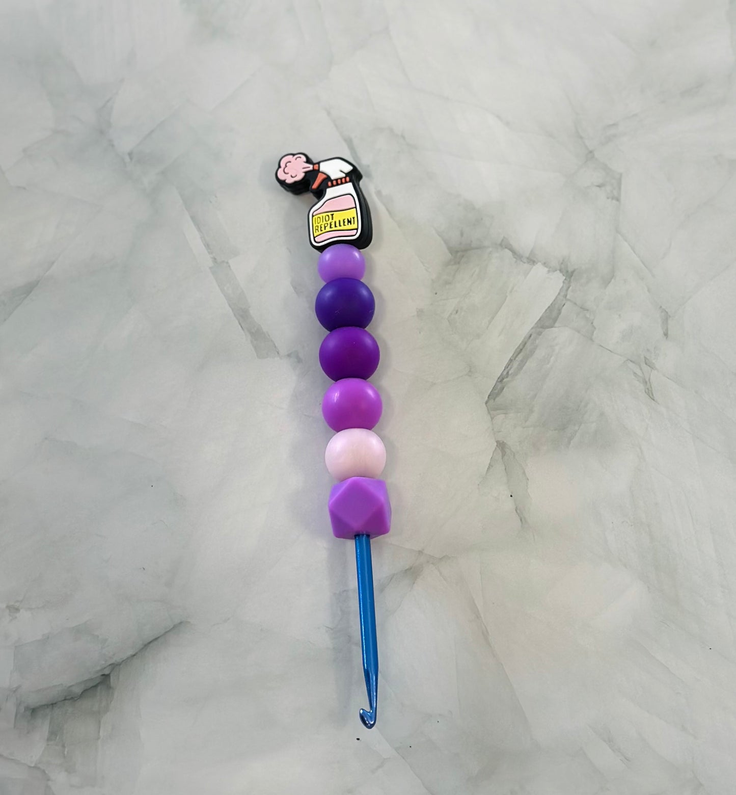 Colorful crochet hook with gradient beads on a marble surface