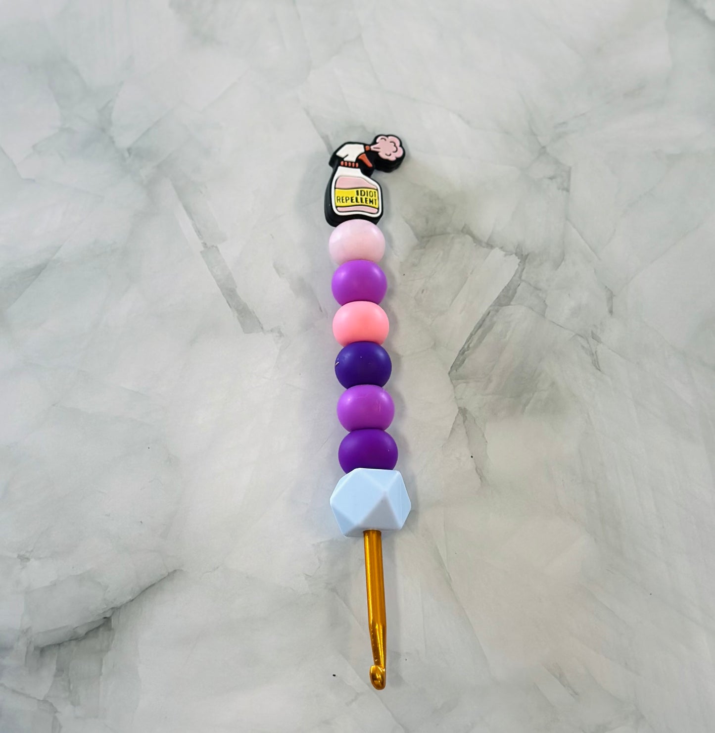 Crochet hook with colorful bead handle on a marble background