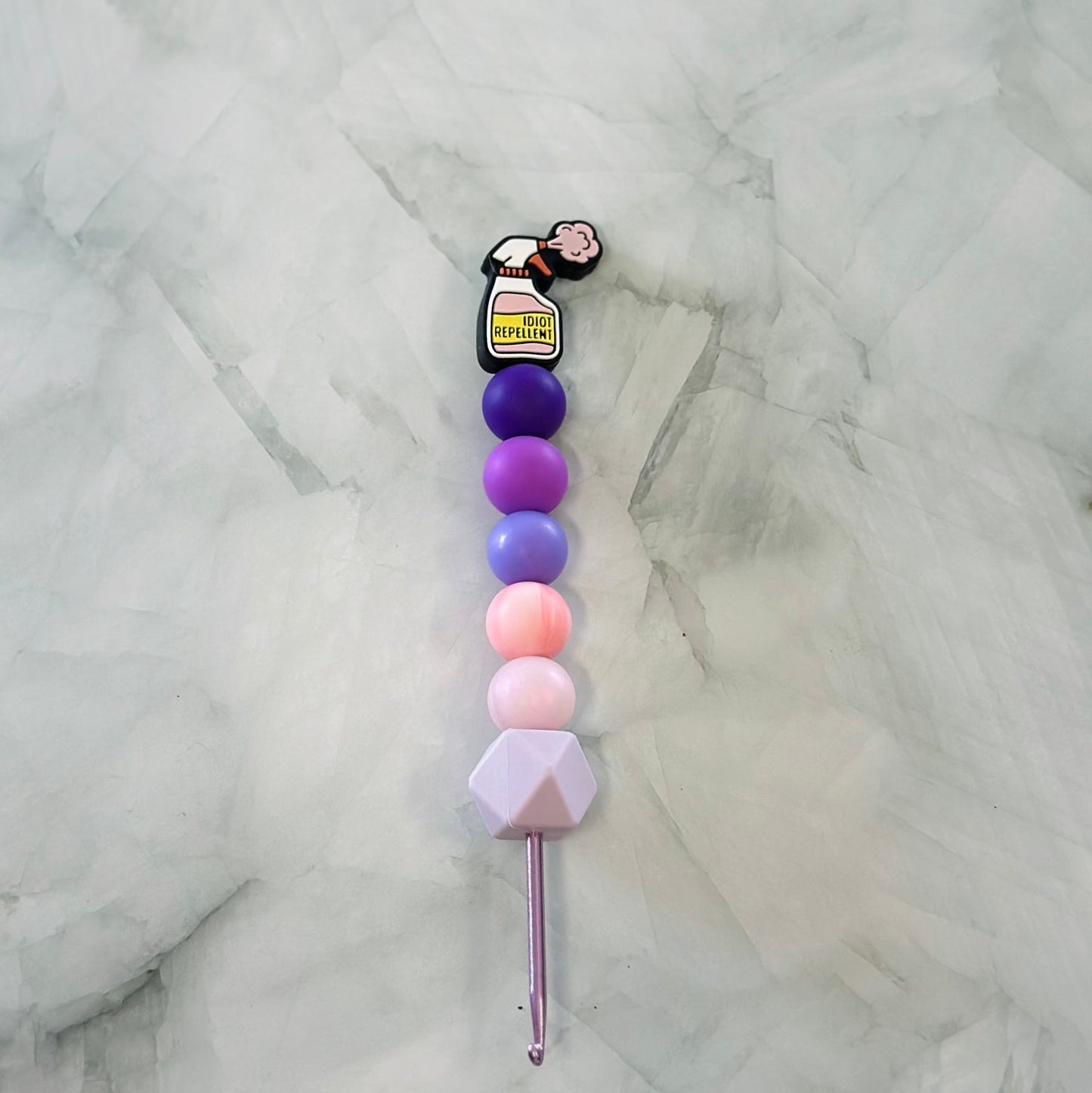 Colorful beaded crochet hook on a marble background