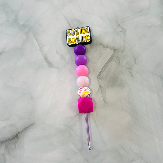 Colorful beaded crochet hook with a label on a marble surface