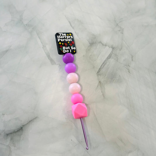 Colorful crochet hook with beads on a marble surface
