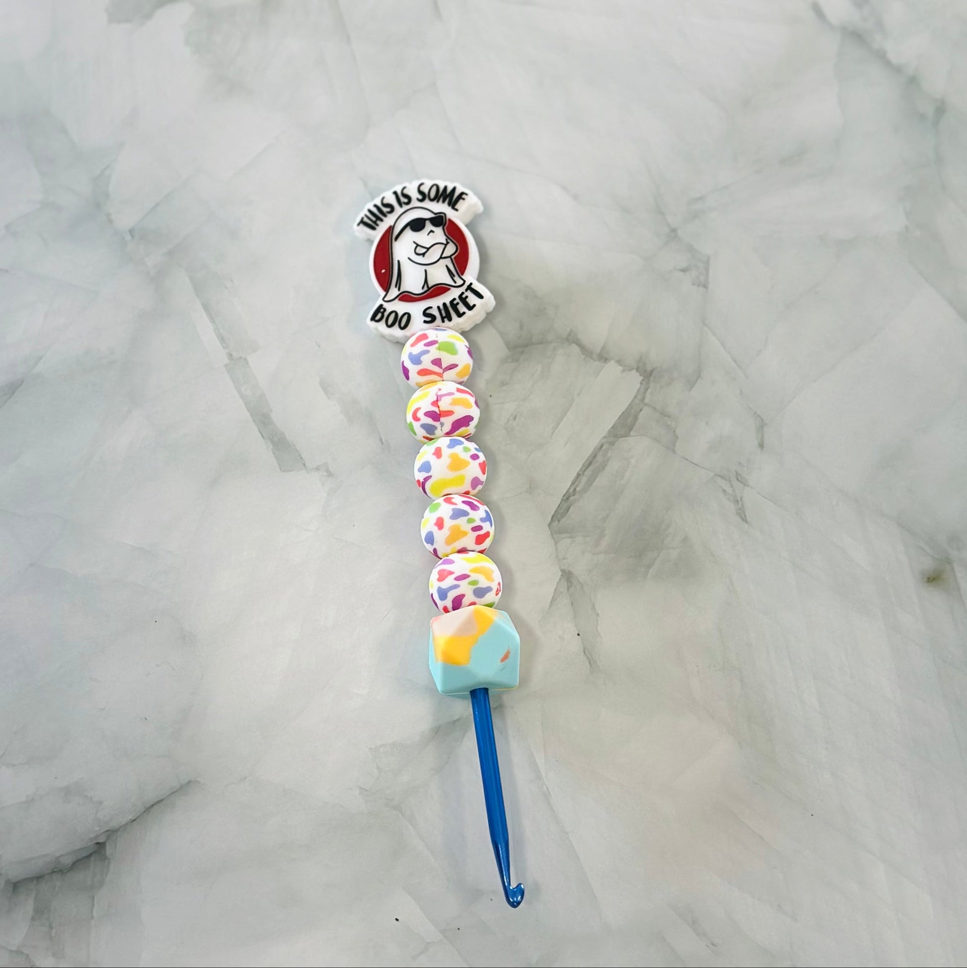 Colorful crochet hook with a cartoon character on a marble surface. 

Acrylic yarn, plush yarn chenille yarn 