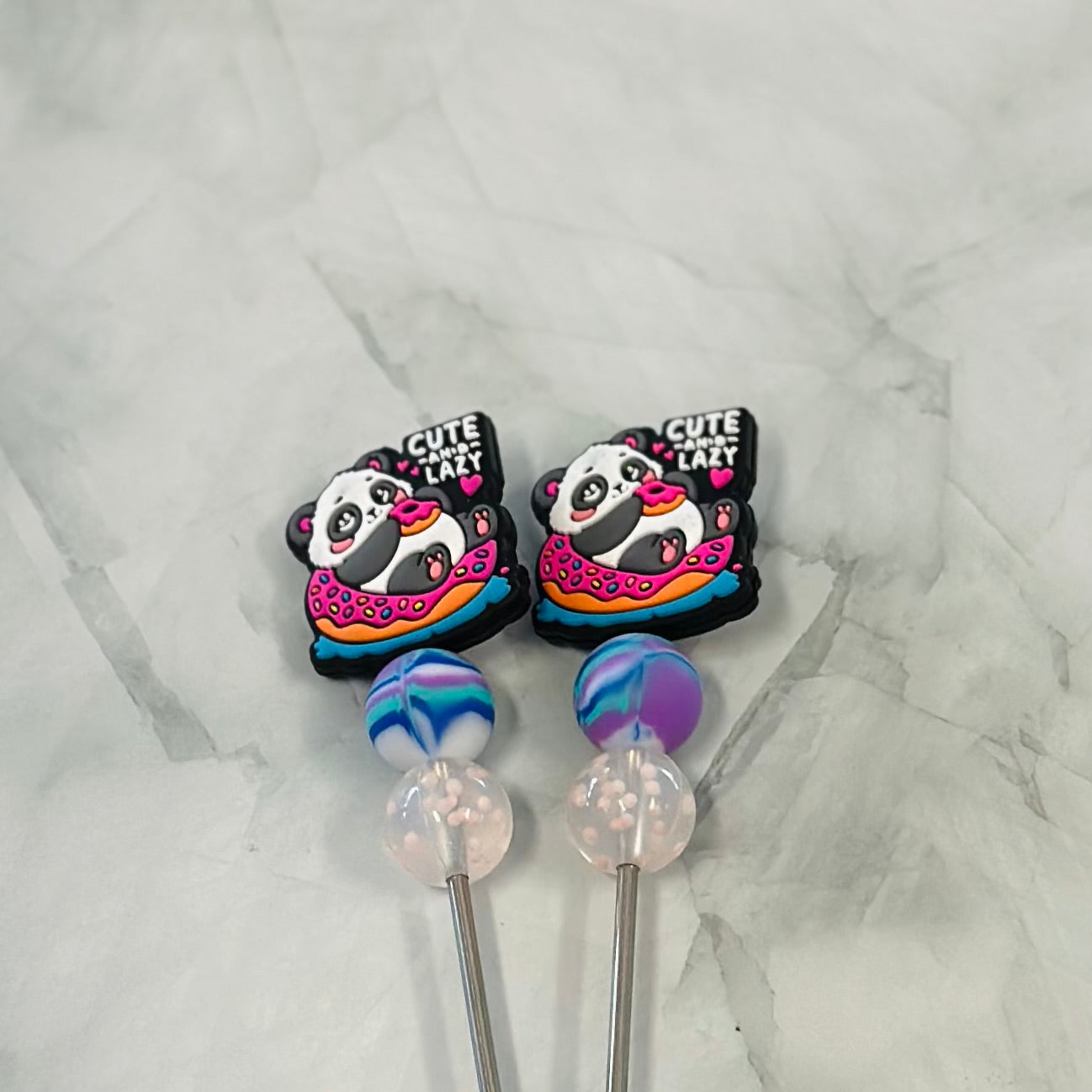 Two panda-themed stitch sticks with colorful designs on a marble surface. Amigurumi plush yarn australia 