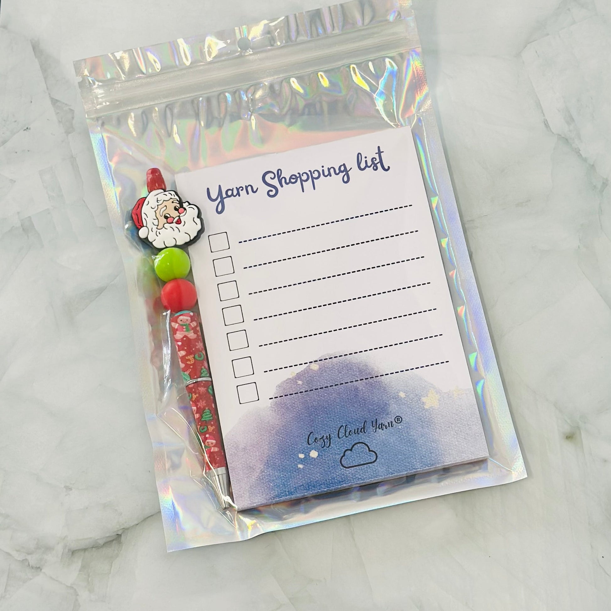 Yarn shopping list with colorful yarn balls in a holographic bag on a marble surface