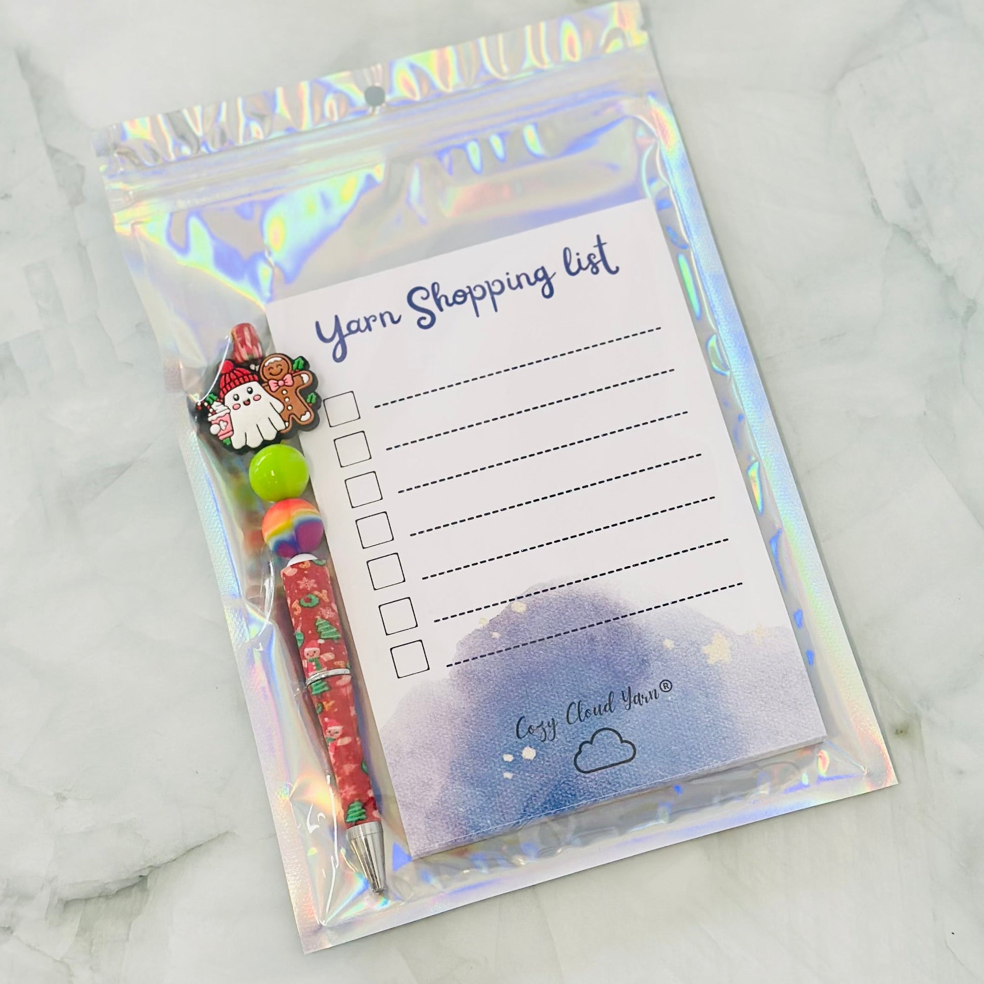 Yarn shopping list with pen and Santa Claus design on a marble background