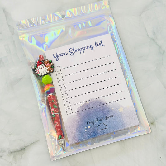 Yarn shopping list with pen and Santa Claus design on a marble background