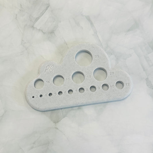 Gray plastic tool with multiple holes in it to suit plush yarn and chenille yarn. A multi tool for all crocheters 