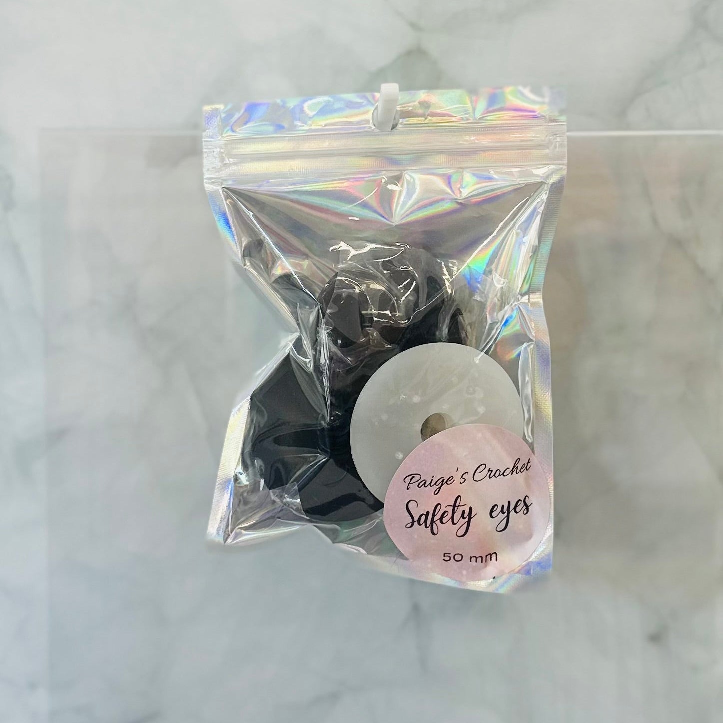 Packaged 50mm safety eyes with a label on a marble background