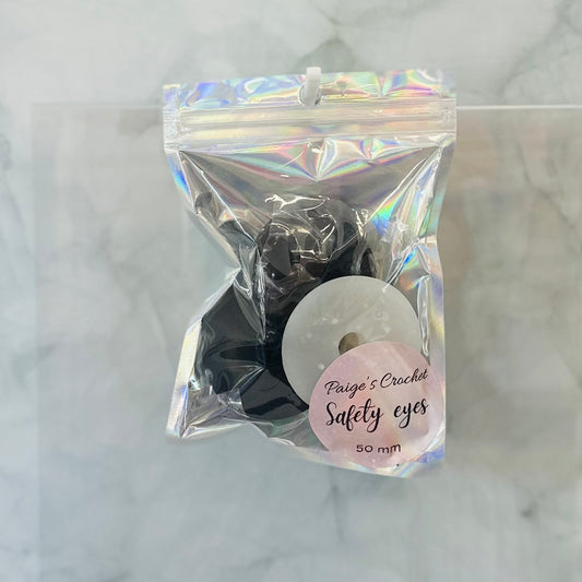 Packaged 50mm safety eyes with a label on a marble background