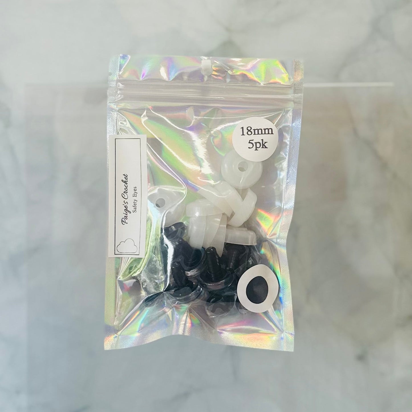 Packaged eyelets with a holographic bag on a textured white background