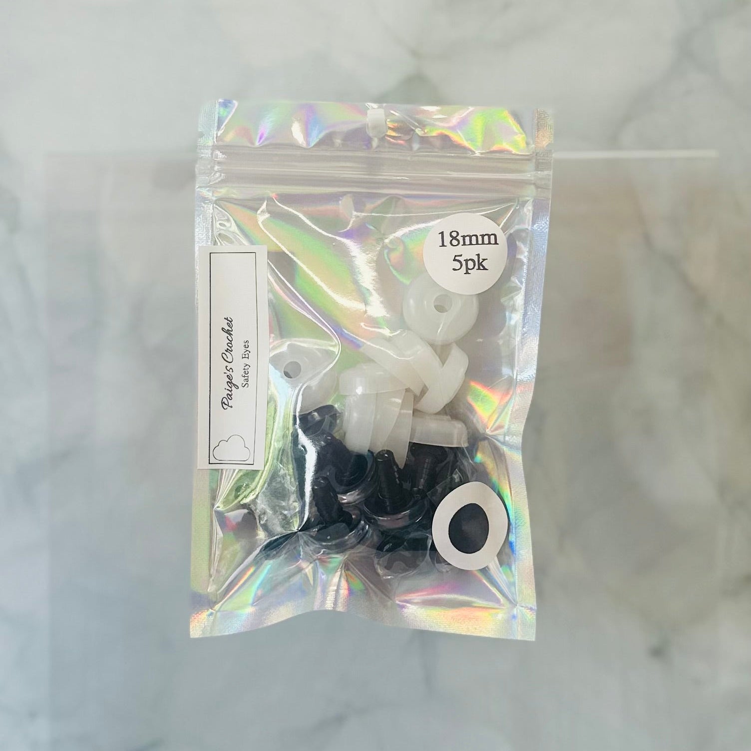 Packaged eyelets with a holographic bag on a textured white background