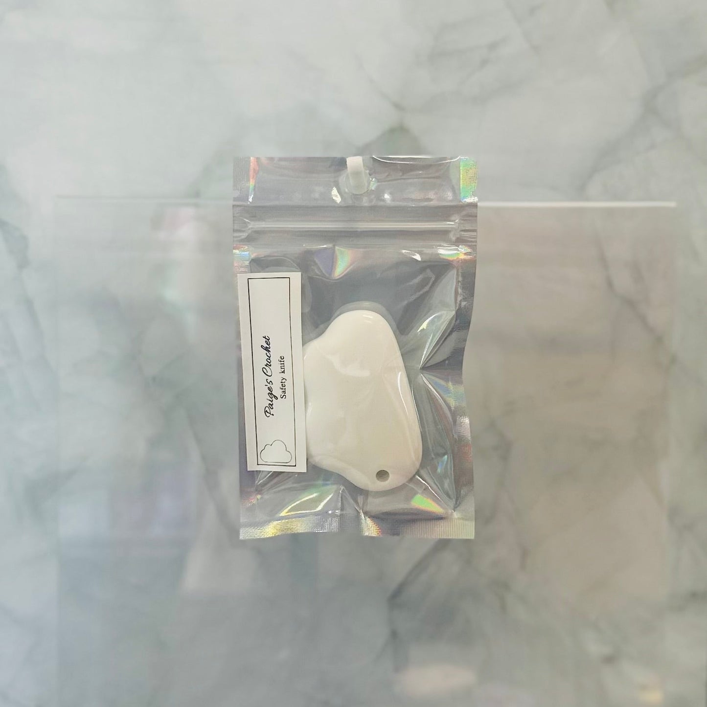 Small white stone with a tag in a clear plastic package on a marble surface