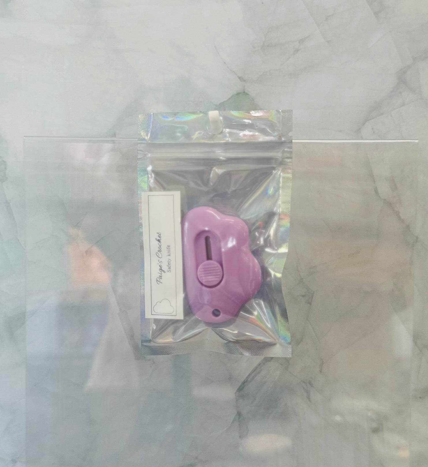 Purple tool in a clear plastic package on a textured white background