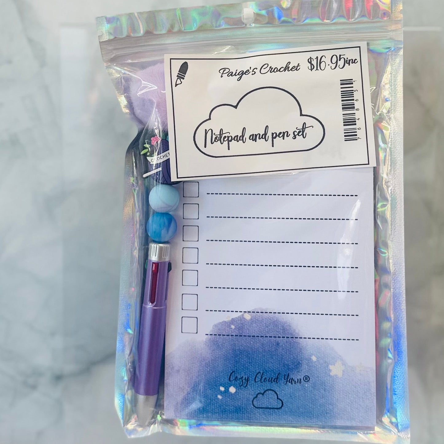 Notepad and pen set with holographic packaging on a marble surface