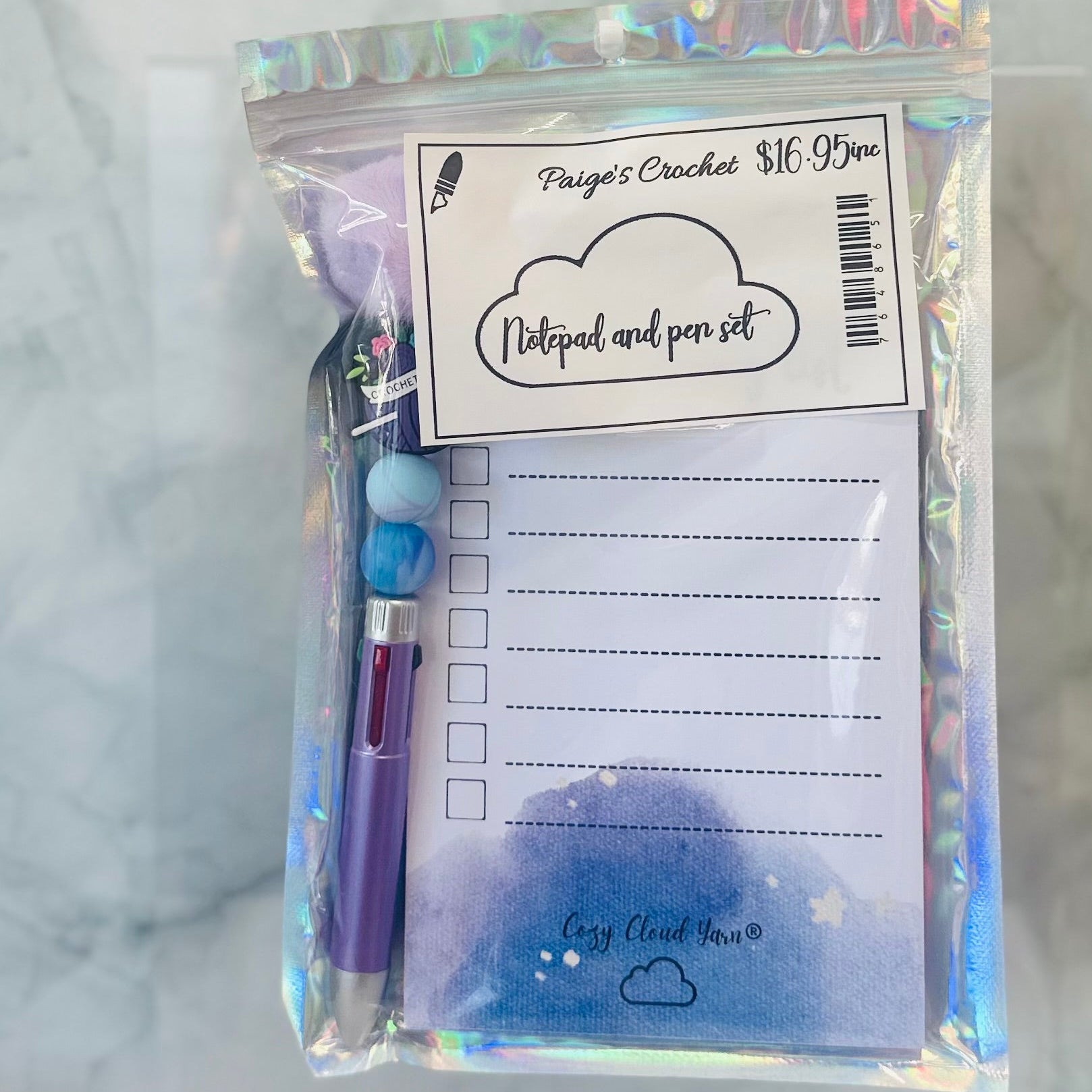 Notepad and pen set with holographic packaging on a marble surface