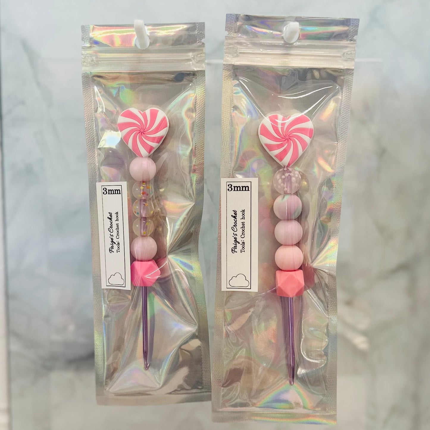 Two packages of decorative sticks with pink and white candy-like tops on a marble background