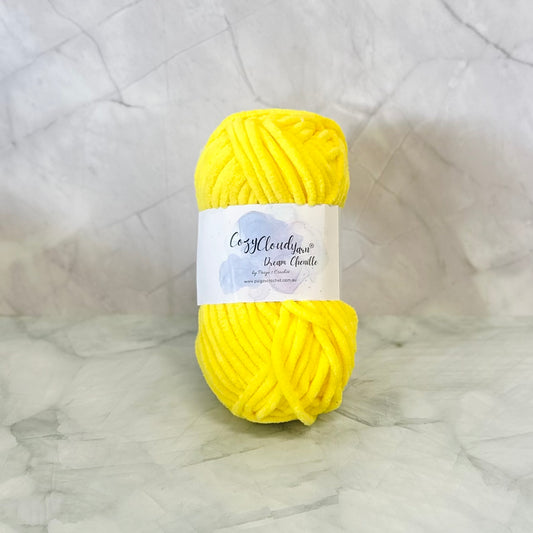 Yellow skein of chenille yarn with a label on a textured gray background