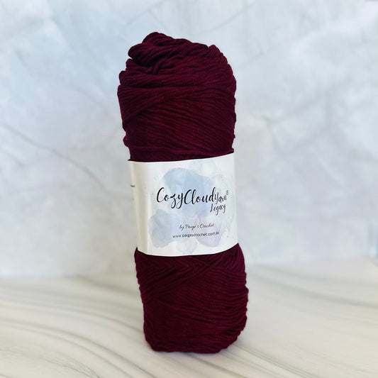Burgundy skein of yarn with a label on a white background