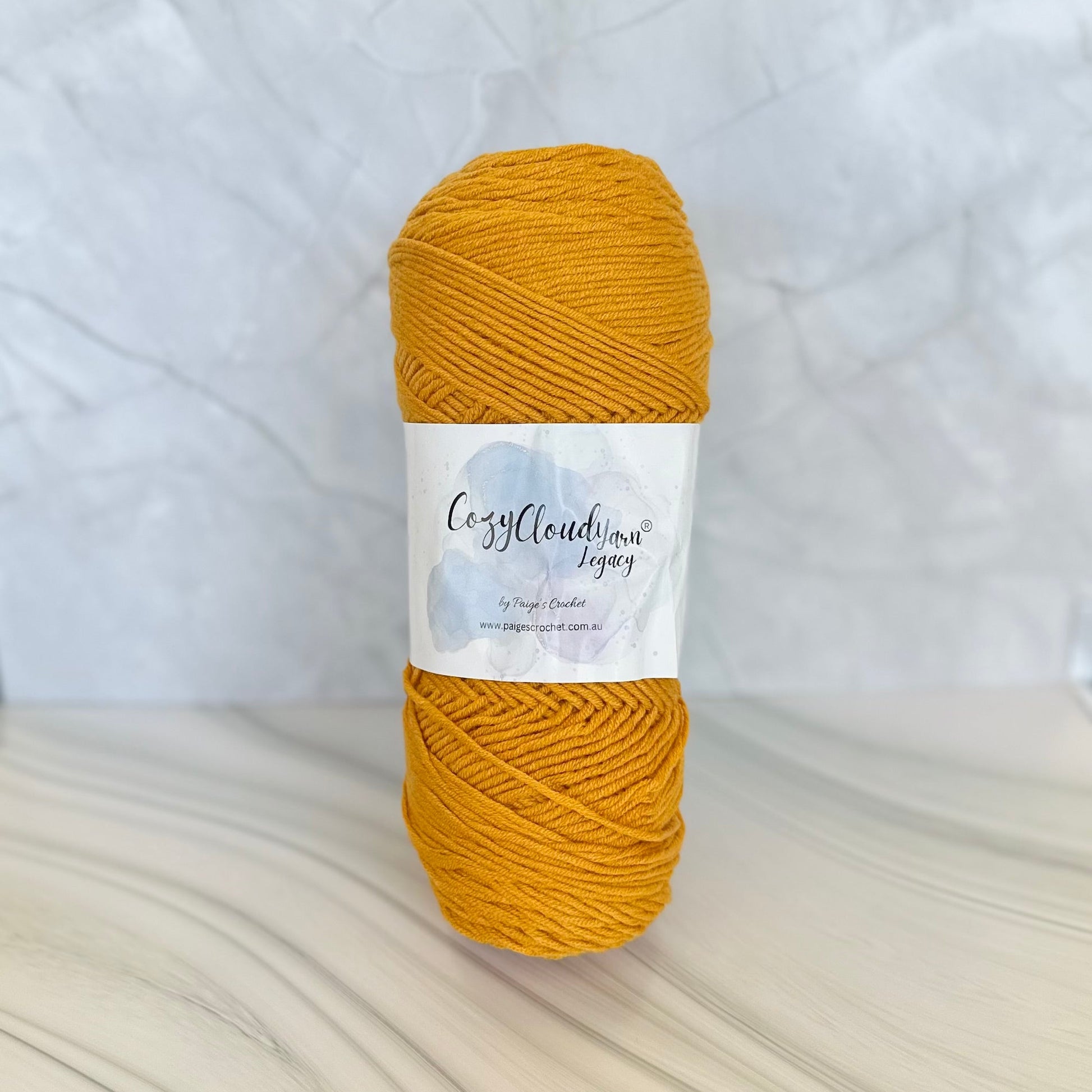 Mustard yellow yarn ball with a label on a white background