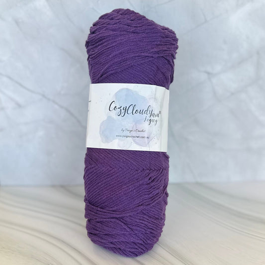 Purple skein of yarn with a label on a light gray background