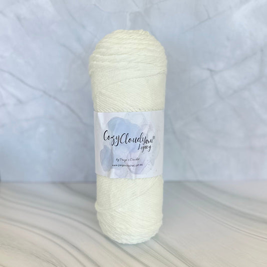 Cream-colored yarn skein with a Cozy Cloud Legacy label on a textured white background