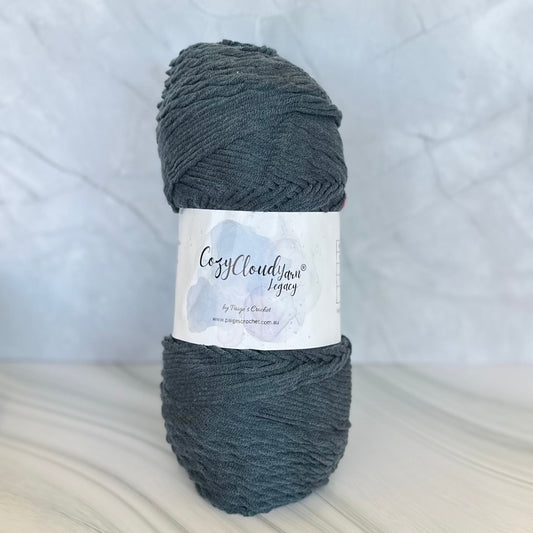 Ball of dark gray yarn with a label on a light wooden surface and white background