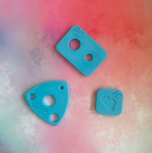 Three blue plastic pieces with cutouts on a multicolored background, This is an assistive tool to install safety eyes in hand made soft toys 